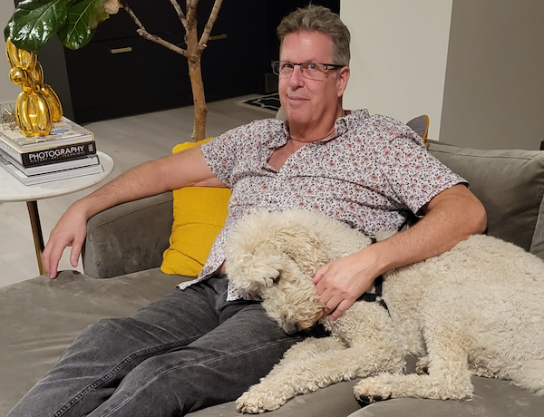 Jeffrey Okyle sitting on couch with dog sleeping on his lap