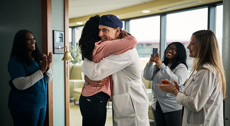 Your legacy creates more patient victories. Doctor and patient embrace at the treatment bell.